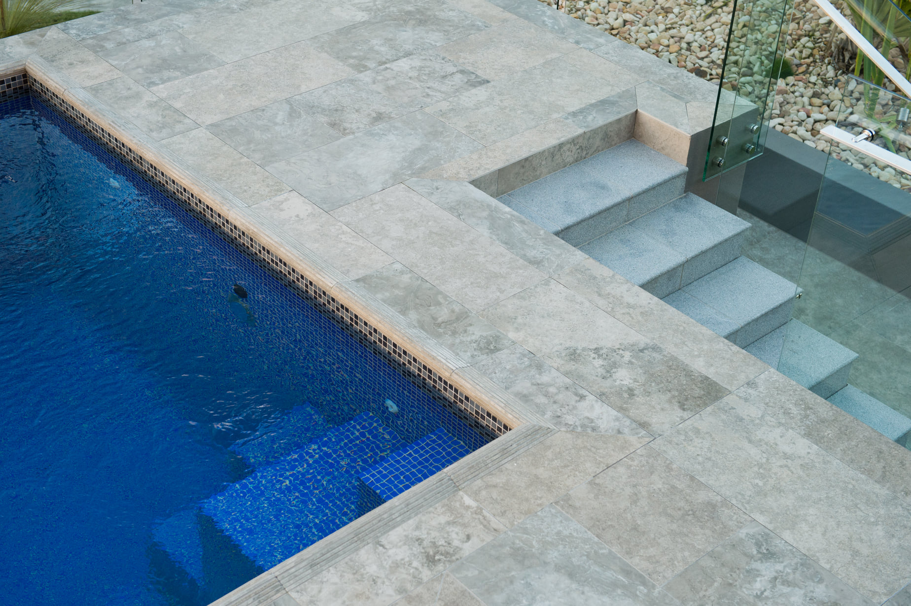 Natural stone paving around a swimming pool.